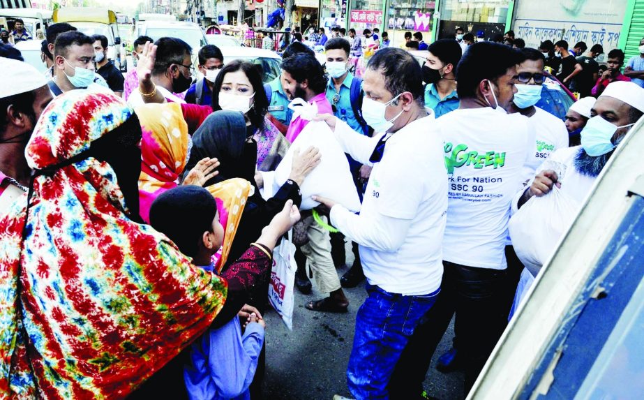 Activists of Go Green, a social organisation distributes foodstuff among the poor on Friday at Bangabandhu Avenue in the city.