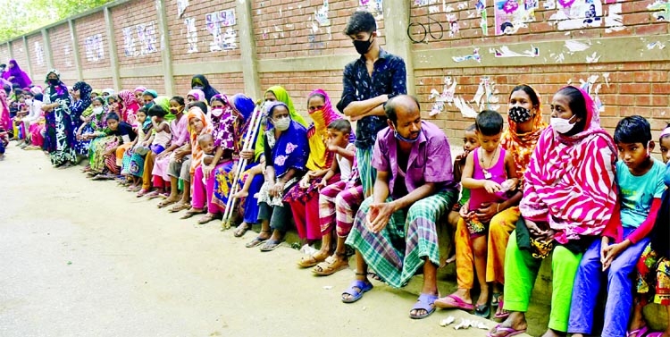 Destitute people wait at a footpaths at Mirpur area in the capital for relief and Zakat gifts ahead of Eid.