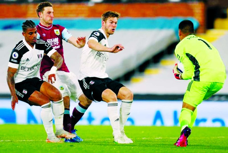 Fulham's midfielder Mario Lemina (left) and Fulham's defender Joachim Andersen (3rd left) close in as Fulham's French goalkeeper Alphonse Areola makes a save from Burnley's New Zealand striker Chris Wood (2nd left) in the English Premier League footba