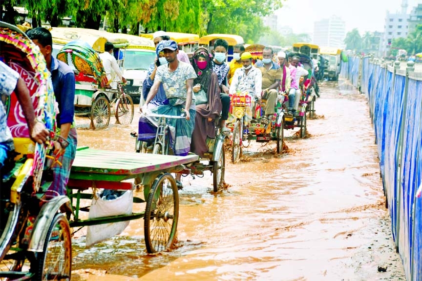 Rickshaw pullers carrying passengers through an waterlogged road after a short spell of rain due to poor drainage system in the capital. This photo was taken from Mir Hazari Bagh area of Doyaganj on Tuesday.