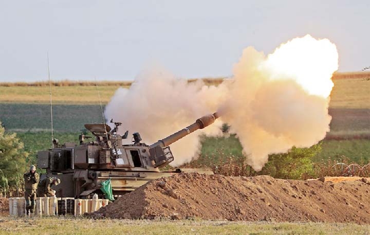 Israeli soldiers fire a 155mm self-propelled howitzer towards the Gaza Strip from their position along the border with the Palestinian enclave.