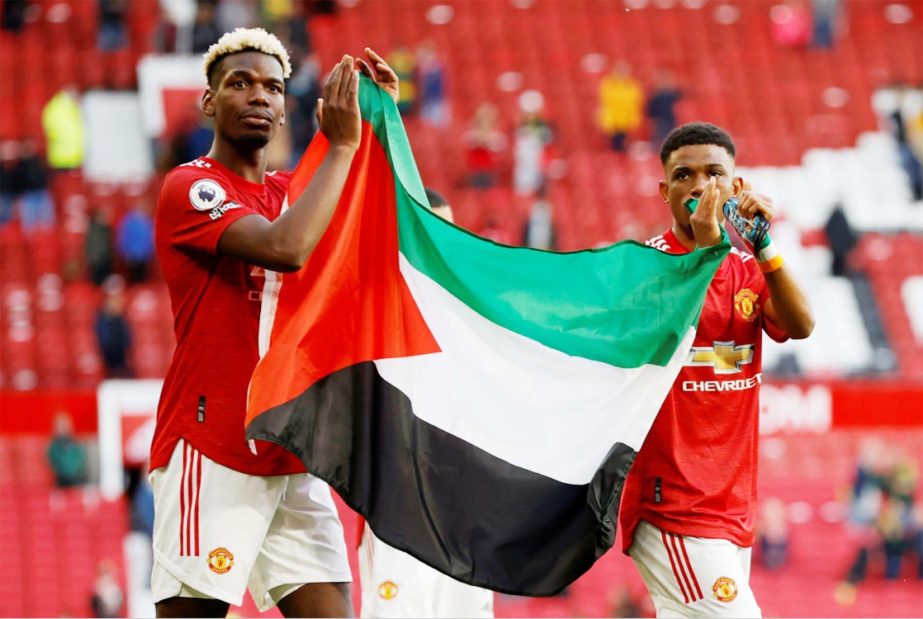 Paul Pogba (left) and Amad Diallo applaud fans while holding a Palestinian flag during a lap of appreciation after the match against Fulham at Old Trafford in Manchester, North West England on Tuesday.