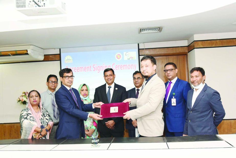 Md. Mahmudul Hossain Khan, Member (Investment Promotion) of Bangladesh Export Processing Zones Authority (BEPZA) and Osamu Sasaki, representative of Matsuoka Corporation (Japan) on behalf of Roulin (BD), exchanging document after signing an agreement at B