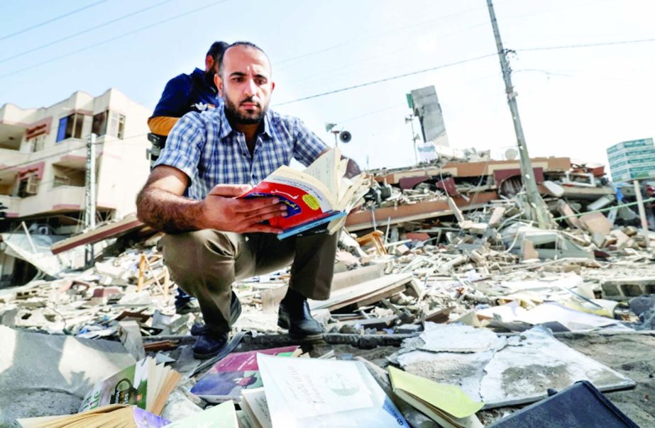 A Palestinian man holds a book he removed from under the rubble of the Kuhail building which was destroyed in an early morning Israeli airstrike on Gaza City.