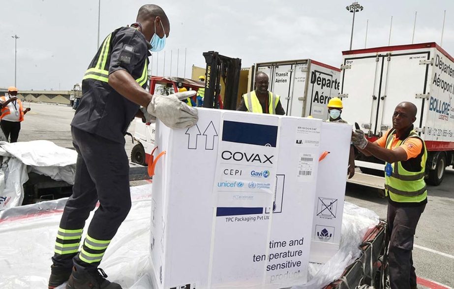 Workers unload a shipment of AstraZeneca Covid-19 vaccine bearing Covax stickers from a plane.