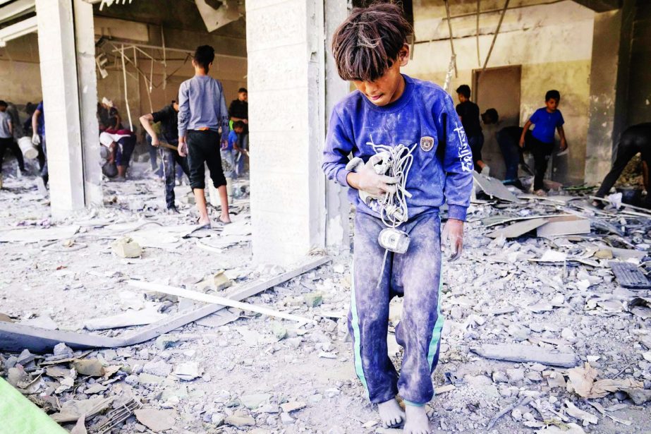 Children scavenge debris from a building that was severely damaged by an air-strike prior to a cease-fire reached after an 11-day war between Gaza's Hamas rulers and Israel, Sunday in Beit Lahia, the Gaza Strip.