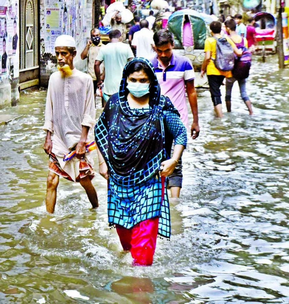 A woman wade through the waterlogged Aga Sadek Road in Old Dhaka after a brief rainfall in the capital on Monday.
