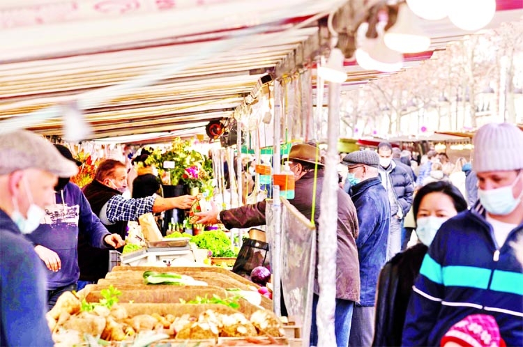 A market stand is protected by see-through plastic sheets to keep a distance between the seller and buyer, as people wearing protective face masks visit the weekly market to shop for vegetables, fruits and dairy products in Paris, France.