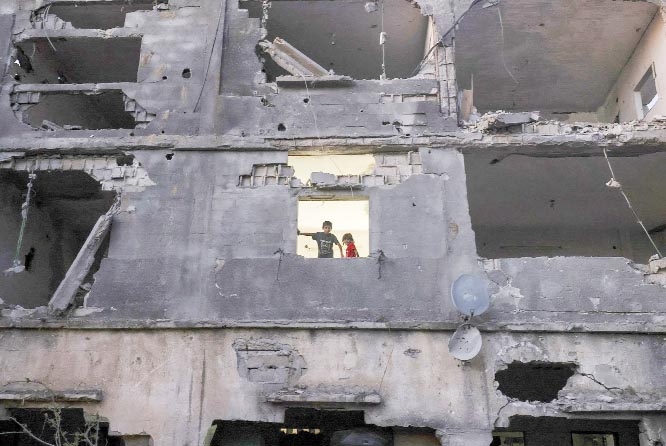 Palestinian children stand near the window of their home in a building heavily damaged during recent Israeli strikes, more than a week after a cease-fire brought an end to 11 days of Israeli attacks, in Beit Hanun in the northern Gaza Strip, Palestine, re