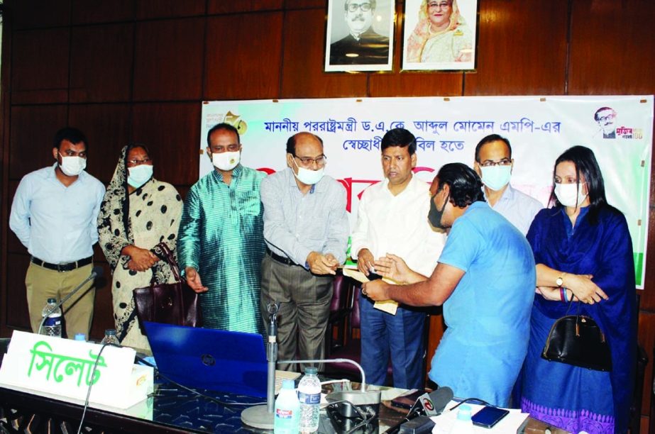 Deputy Commissioner of Sylhet, Kazi Emdadul Haque distributes cheques as gift of the voluntary fund of Foreign Minister Dr AK Abdul Momen among the poor of the district on Sunday.