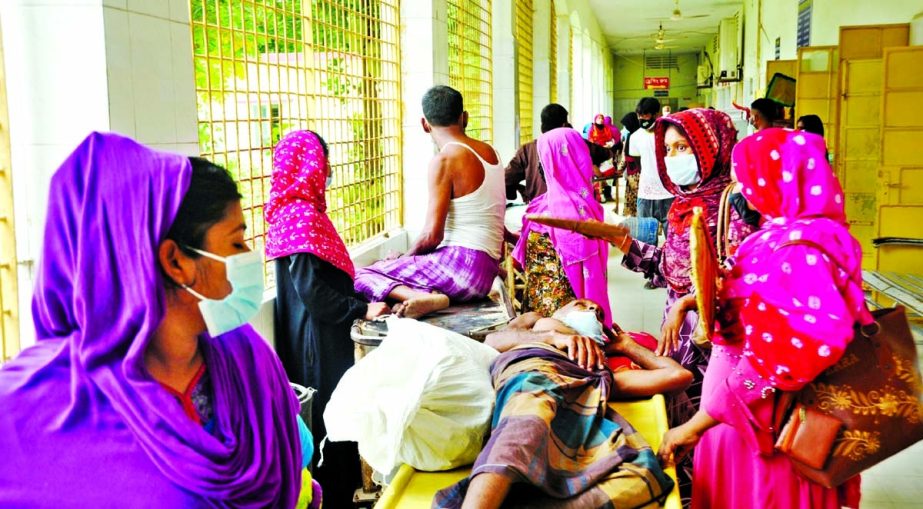 Patients sit and lie down on the floor of a corridor at the Rajshahi Medical College Hospital which struggles with inadequate capacity following the surge in Covid cases.