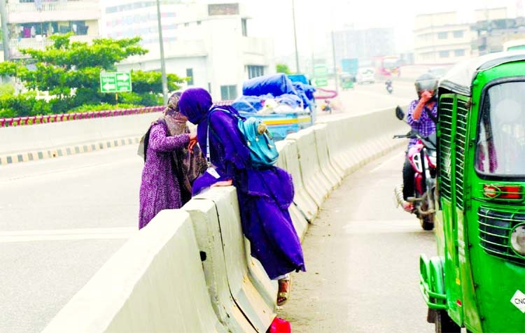 Two women crossing the road median risking their lives at Mayor Hanif Flyover in the capital on Sunday despite ban on pedestrian movement on the flyover.