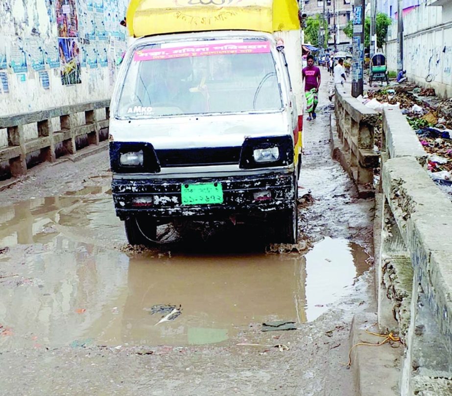 Pedestrians and motorized vehicles struggle through the dilapidated road of Compani- ghat in Kamrangirchar in the city on Monday. The situation remains the same for long but the authority concerned seemed to be blind to repair the road to mitigate the woe