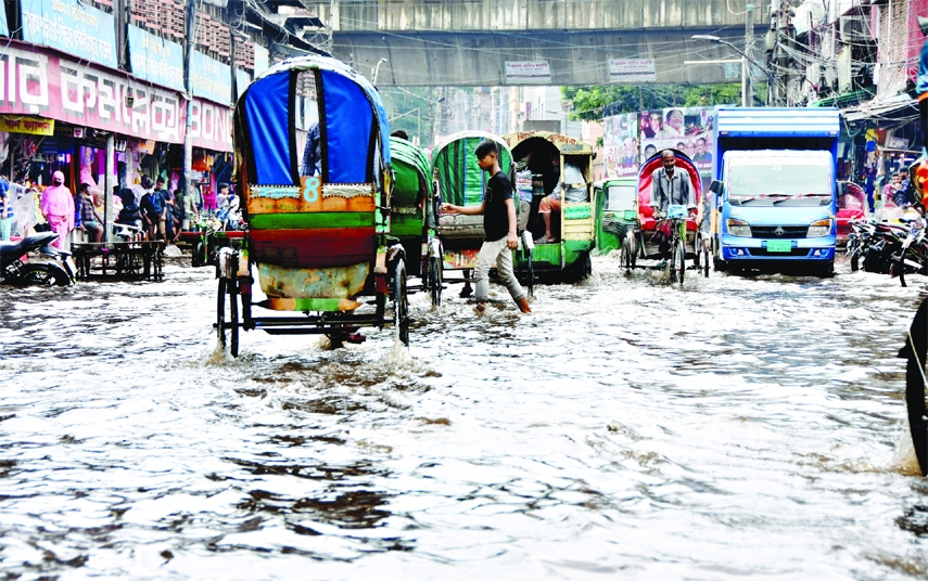 Rickshaws and other vehicles ply on a waterlogged road in front of Bangabazar area in the capital on Saturday after a short spell of rain due to poor drainage system.
