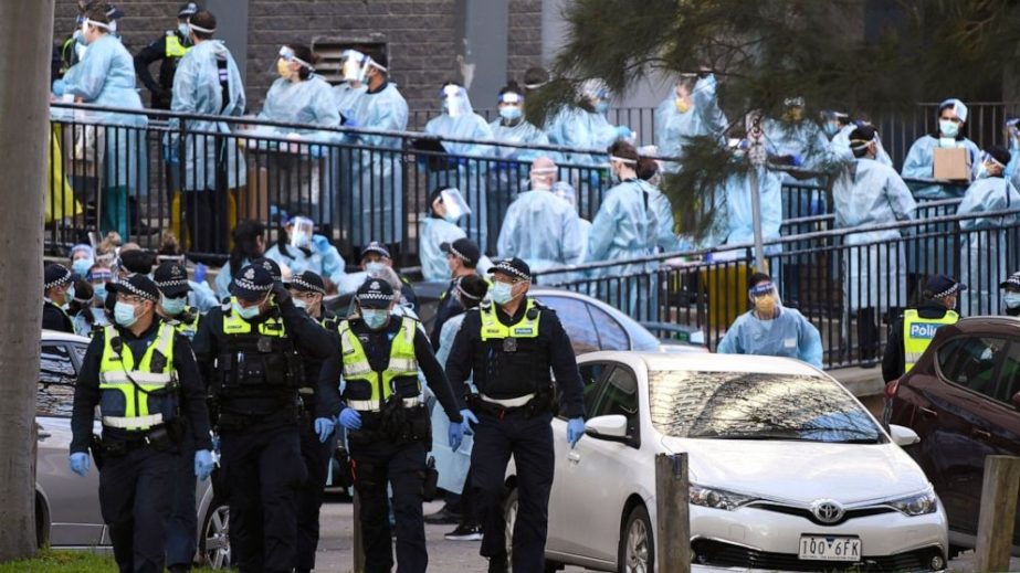 Police officers and healthcare workers are stationed outside a public housing tower that is locked down as a Coronavirus hotspot in Melbourne, Australia. (File phoro)