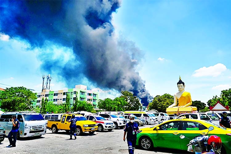 A Buddha statue is seen as smoke billows from an explosion and fire at a plastics factory in Bangkok, Thailand on Monday.