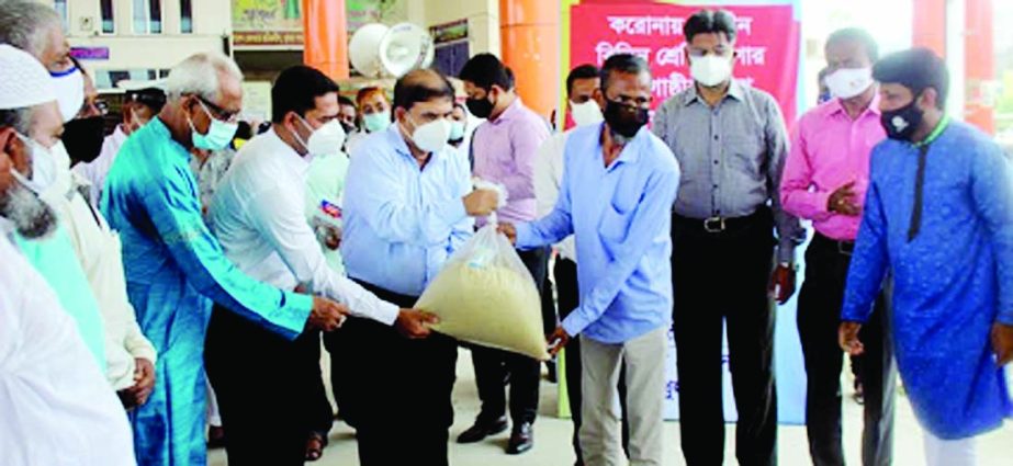 Divisional Commissioner of Khulna Md Ismail Hossain distributes rice, potatoes, pulse, oil and soap among 438 jobless and destitute people on the city's Railway Station premises on Tuesday as part of the instant humanitarian support programme by Prime Mi