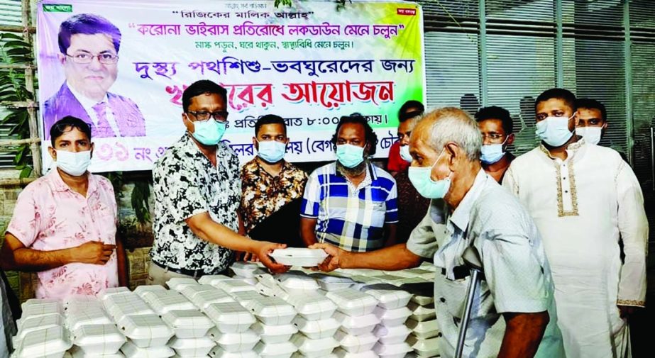 Councilor of 31 No. Ward of DSCC Sheikh Mohammad Alamgir distributes food among the street children during lockdown. The snap was taken from the city's Begum Bazar Chowrasta on Tuesday.