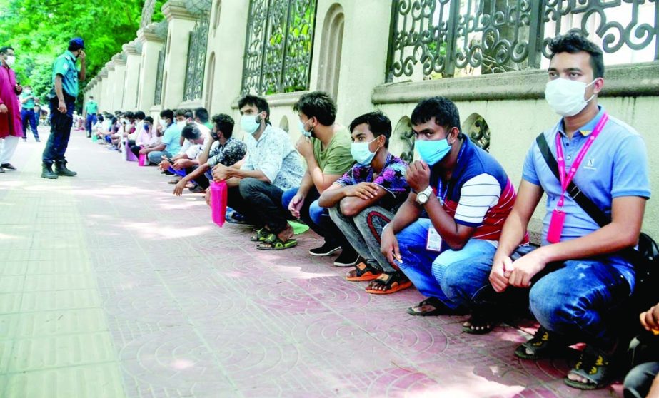 Law enforcers keep some persons sitting for coming out from their residences unnecessarily during lockdown. The snap was taken from in front of RAJUK building on Tuesday.