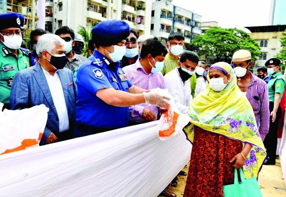 IGP Dr. Benazir Ahmed distributes food and cash among the destitute at a ceremony organised by Bangladesh Shop Owners Association at the playground of Siddheshwari High School in the city on Thursday.