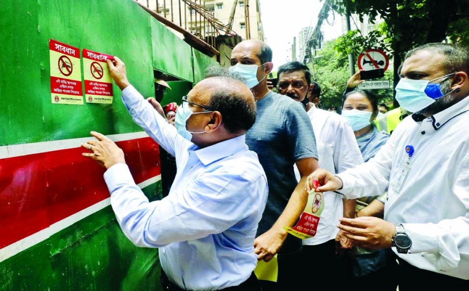 LGRD and Cooperatives Minister Tajul Islam pasting stickers at different places in the city's Gulshan Avenue on Saturday with a view to raising awareness against dengue disease.