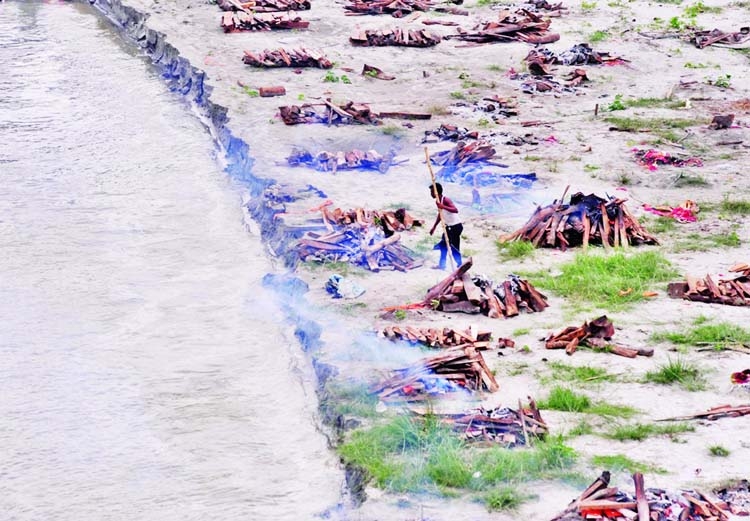 A municipal worker cremates bodies that washed up on the Ganges riverbank after monsoon rains swelled the river and exposed bodies buried in shallow sand graves during the peak of the latest wave of Covid-19 in Phaphamau on the outskirts of Prayagraj, Ind