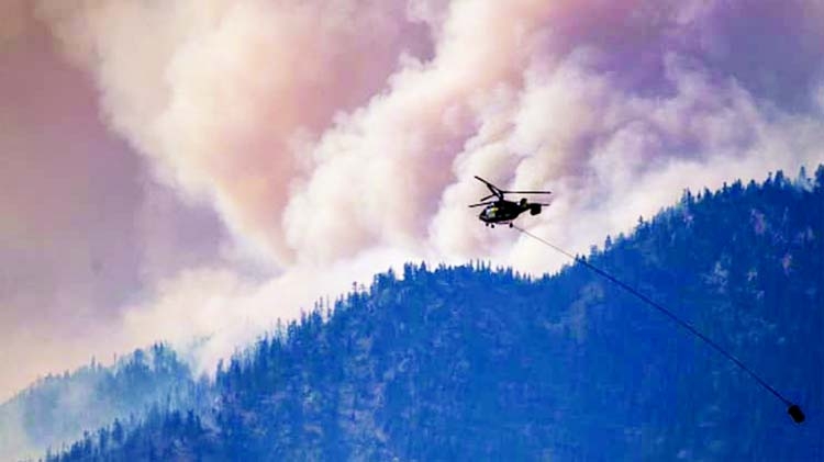 A helicopter prepares to make a water drop as smoke billows along the Fraser River Valley near Lytton, British Columbia, Canada, on Friday.