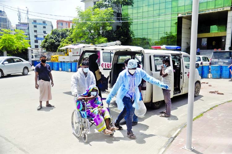 Two people carry a woman from an ambulance with the help of a wheelchair to the Mohakhali DNCC Dedicated Covid-19 Hospital in the capital on Sunday.