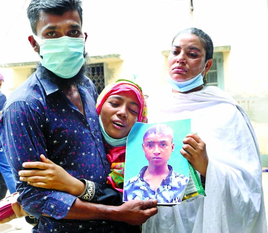 A mother holding her son's photo at the Dhaka Medical Collage Hospital yesterday as relatives of missing workers of Hashem Foods factory frantically rushed from hospital to hospital in the search of their loved ones.