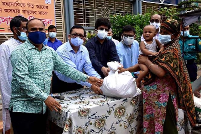 Secretary of Disaster Management and Relief Md. Mohsin and members of BCS 9th Batch Forum Welfare Foundation distribute essentials among the destitute in the city's Bhatara area on Friday.