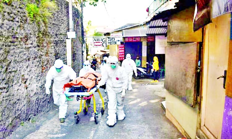 Health workers carry the body of a person who died with Covid-19 while isolating at home in Bandung, Indonesia.