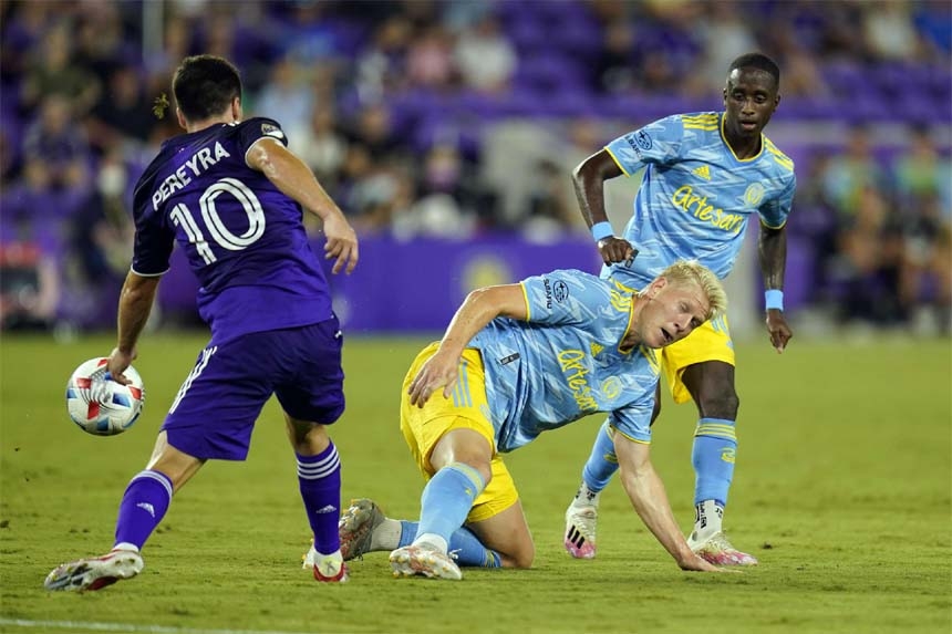 Philadelphia Union defender Jakob Glesnes (center) slips to the turf as he tries to stop Orlando City midfielder Mauricio Pereyra (left) from advancing the ball during the first half of an MLS soccer match in Orlando, Fla on Thursday.