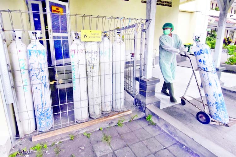 A medical worker pulls an oxygen cylinder to be delivered to the emergency ward at a government-run hospital amid the COVID-19 outbreak in Denpasar, Bali, Indonesia.
