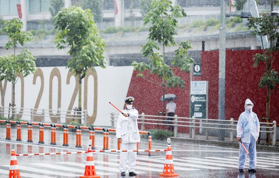 Traffic policemen control the traffic in front of the Olympic stadium in the rain caused by tropical storm Nepartak in Tokyo, Japan on Tuesday