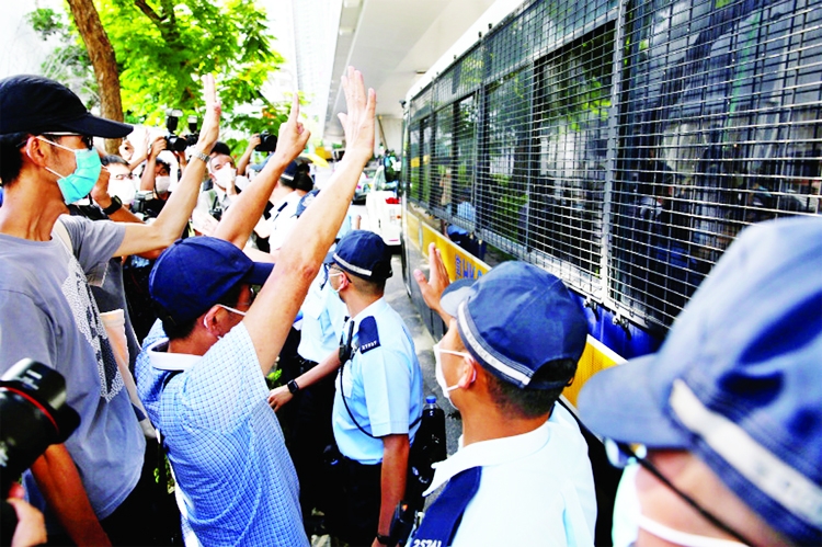 Supporters of Tong Ying-kit, the first person charged under the new national security law, greet a prison van outside West Kowloon Magistrates' Courts in Hong Kong.