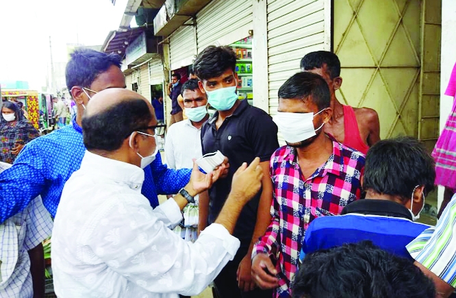 Former Joint Secretary of BNP students' wing central committee Abdul Karim Sarker distributes masks among the pedestrians at Sadar Bazar of Fulbaria upazila, Mymensing on Wednesday.