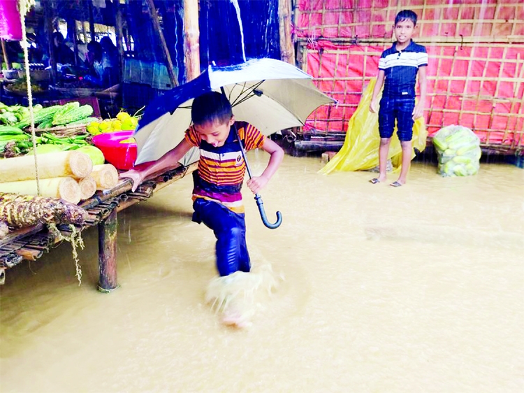 A boy plays in the flooded road after heavy monsoon rains triggered flooding at Kutapalong refugee camp, in Cox's Bazar. Picture obtained from a social media.