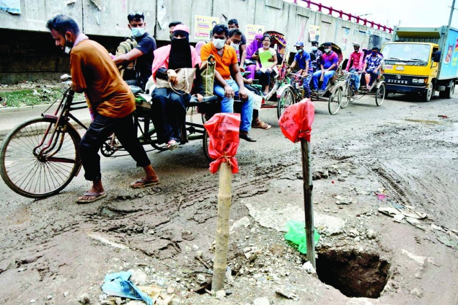 Pedestrians and also passengers struggle through the pothole strewn road in the city's Jatrabari area on Saturday.