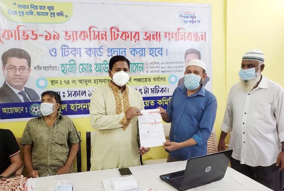 Councillor of 33 No Ward of DSCC Awal Hossain hands over vaccine card at the free registration of Covid-19 vaccine and vaccine card distribution ceremony organised by Abul Hasnat Road Purba Panchaet Committee at his office in the city on Monday.