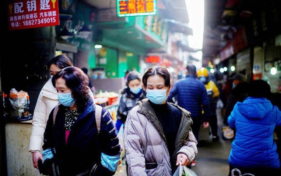 People wearing face masks walk on a street market, following an outbreak of the coronavirus in Wuhan, Hubei province, China.