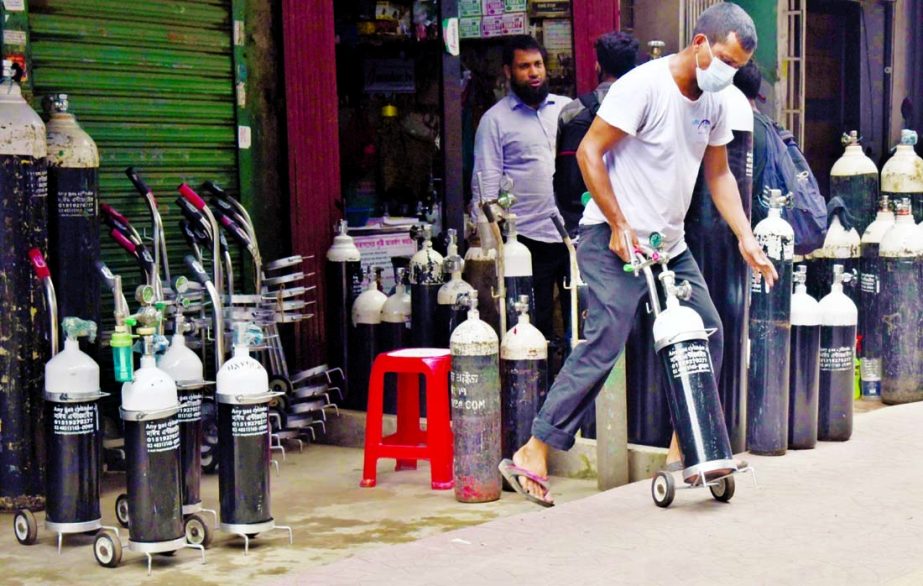 A customer is seen taking an oxygen cylinder from a shop at Moghbazar area in the capital on Tuesday amid Covid-19 pandemic across the country.