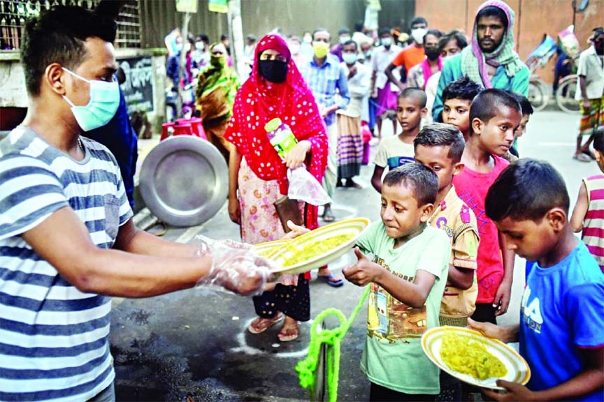 A volunteer from Mehmankhana distributing food to the pandemic-affected children at Lalmatia area in Dhaka.
