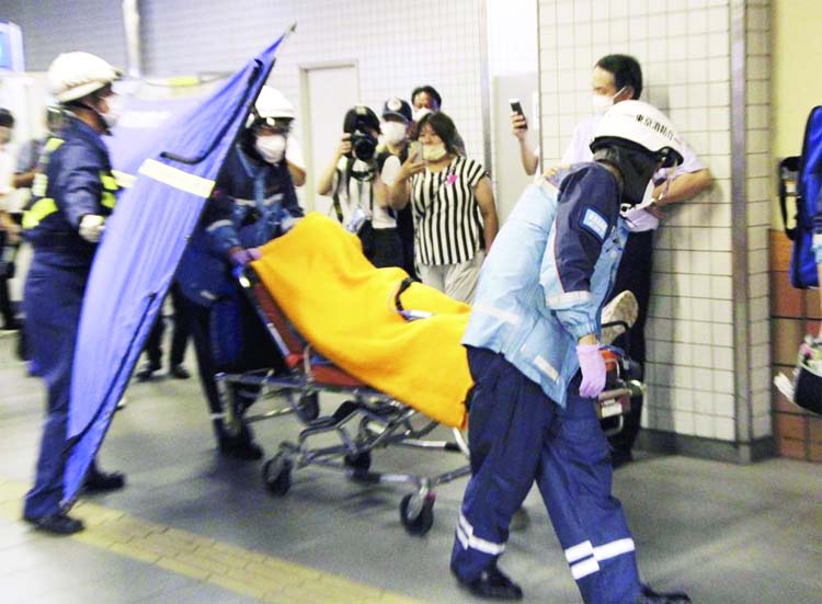 Rescuers carry an injured passenger on stretcher at Soshigaya Okura Station after stabbing on a commuter train, in Tokyo Friday night.