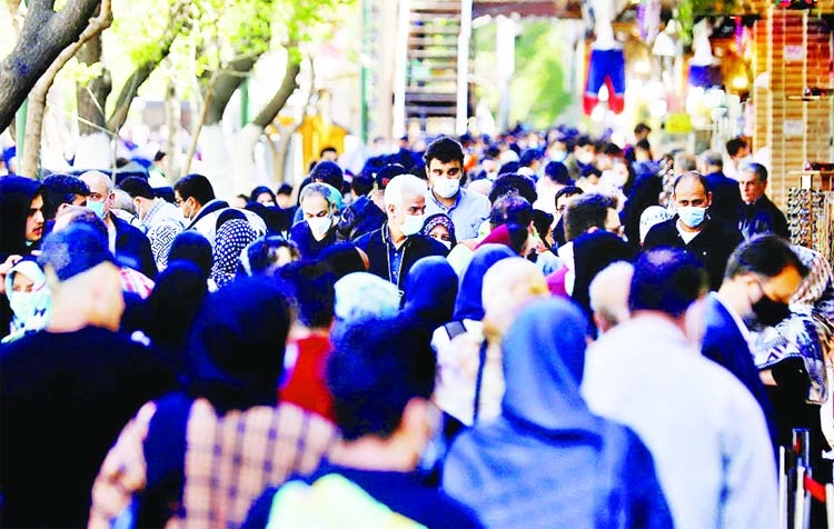 Iranians wearing protective face masks against the coronavirus walk in a crowded area of the capital Tehran, Iran.