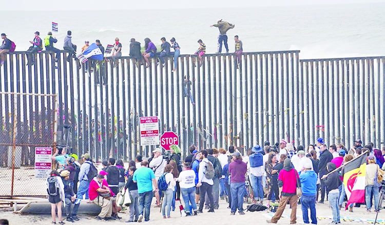 Pro-migrant caravan demonstrators climb the US-Mexico border fence during a rally in San Ysidro, California.