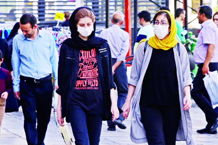 Iranians, some wearing face masks, walk along a street in the capital Tehran amid the coronavirus pandemic crisis.