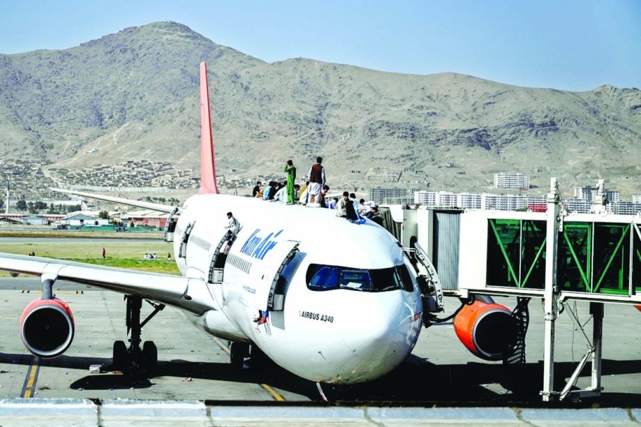 Afghans in desperation to flee country climb atop an aircraft after filling its inside to capacity at the Kabul Airport on Monday.