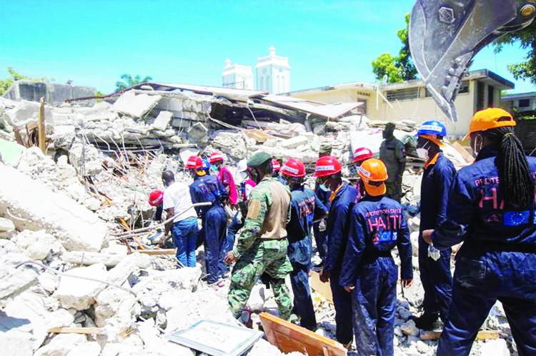 Members of a rescue and protection team clean debris from a house after a 7.2 magnitude earthquake in Les Cayes, Haiti on Sunday.