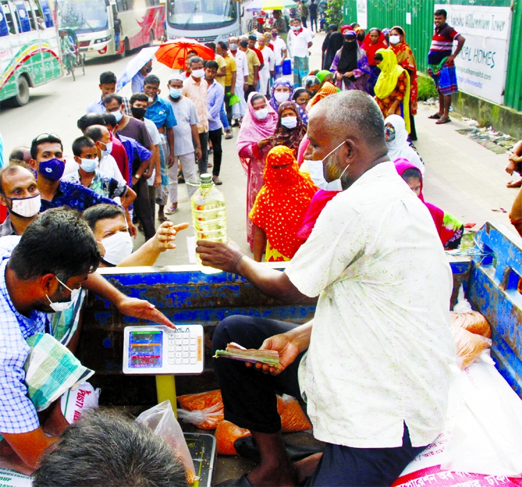 People stand in long queues at the Malibagh area of the capital on Monday to buy TCB OMS products.