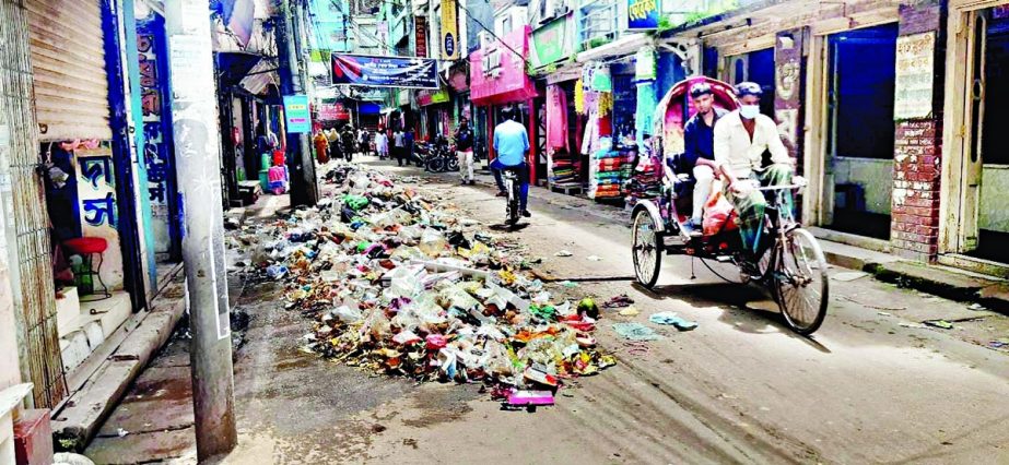 A rickshaw goes by a pile of garbage left unattended in Barishal city on Saturday as cleaners went on work abstention. NN photo